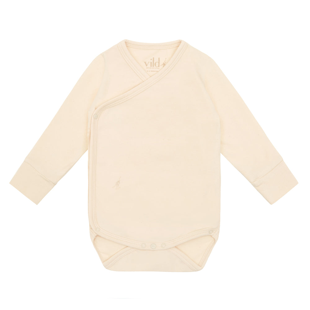 Organic kimono bodysuit. Brand: Vild  Colour: Ecru Details: Long sleeves, Crossover neck, Snapper engraved details for quick assembly, Eco-conscious, Soft, Perfect weight for warmer weather Composition: 5% Organic Cotton, 5% Elastane Made in: Portugal